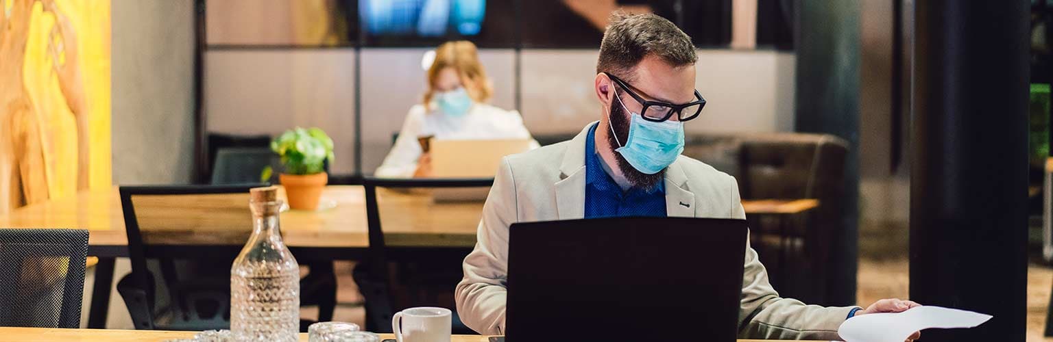  man working on a laptop wearing a facemask